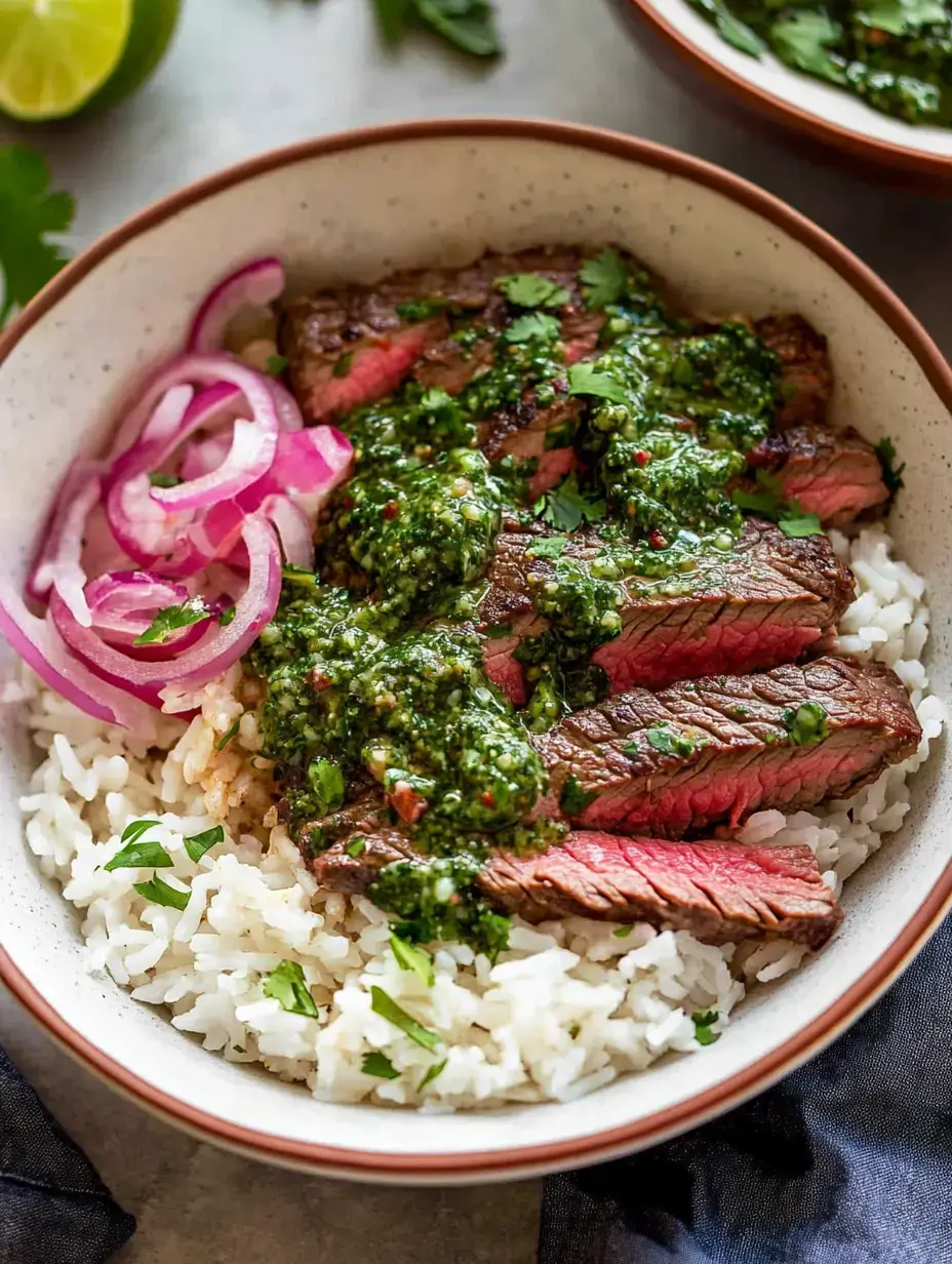 Eine Schüssel Reis, darüber geschnittenes Steak, grüne Sauce, garniert mit Koriander und roten Zwiebelringen.