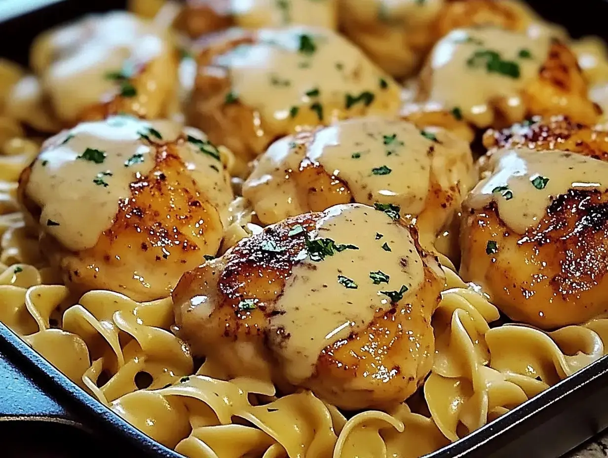 Pfanne gefüllt mit Eiernudeln, Hähnchenschenkel, cremiger Sauce und frischer Petersilie.