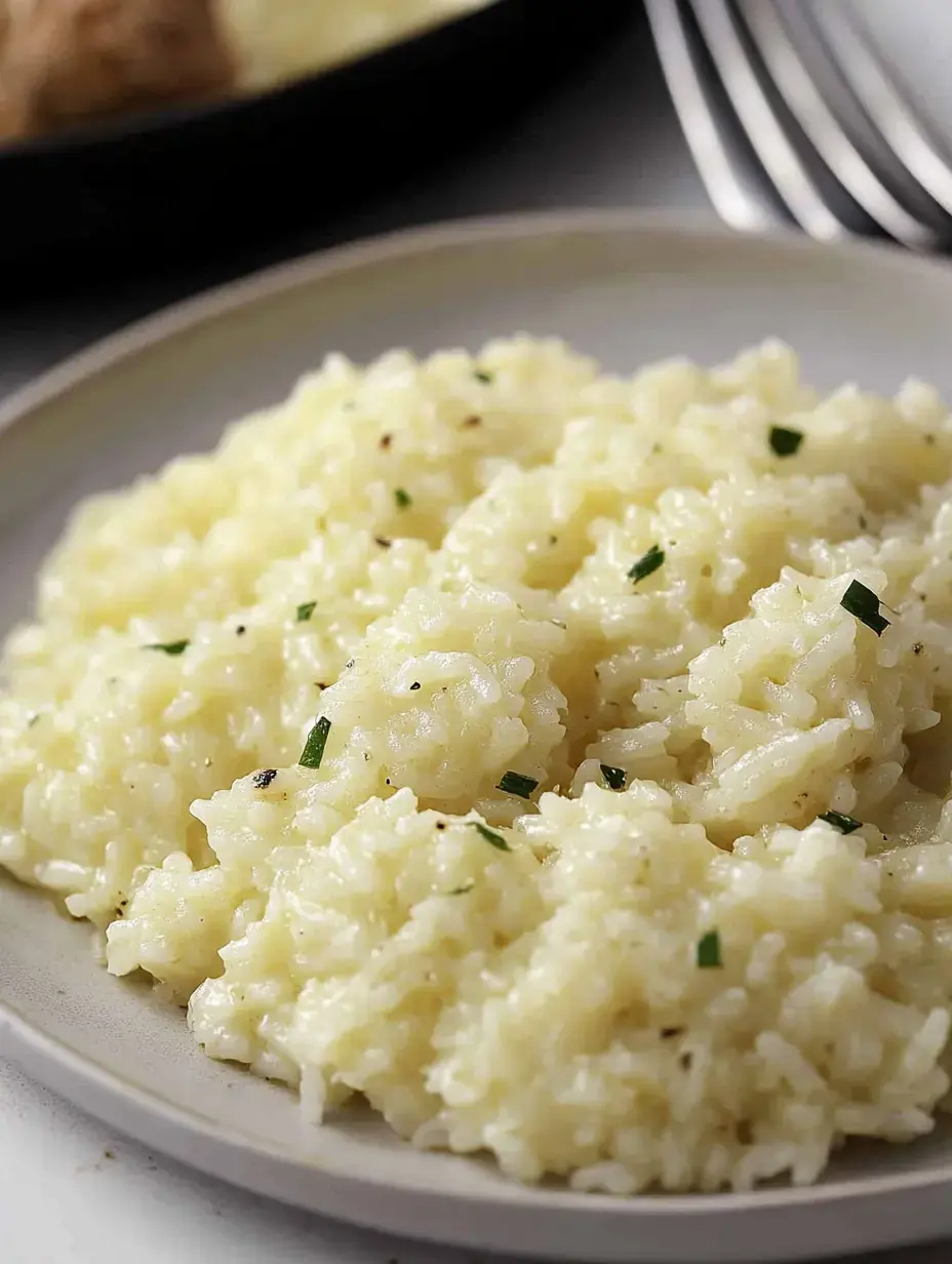 Eine Portion cremiges, kräuterinfundiertes Risotto auf einem hellen Teller.