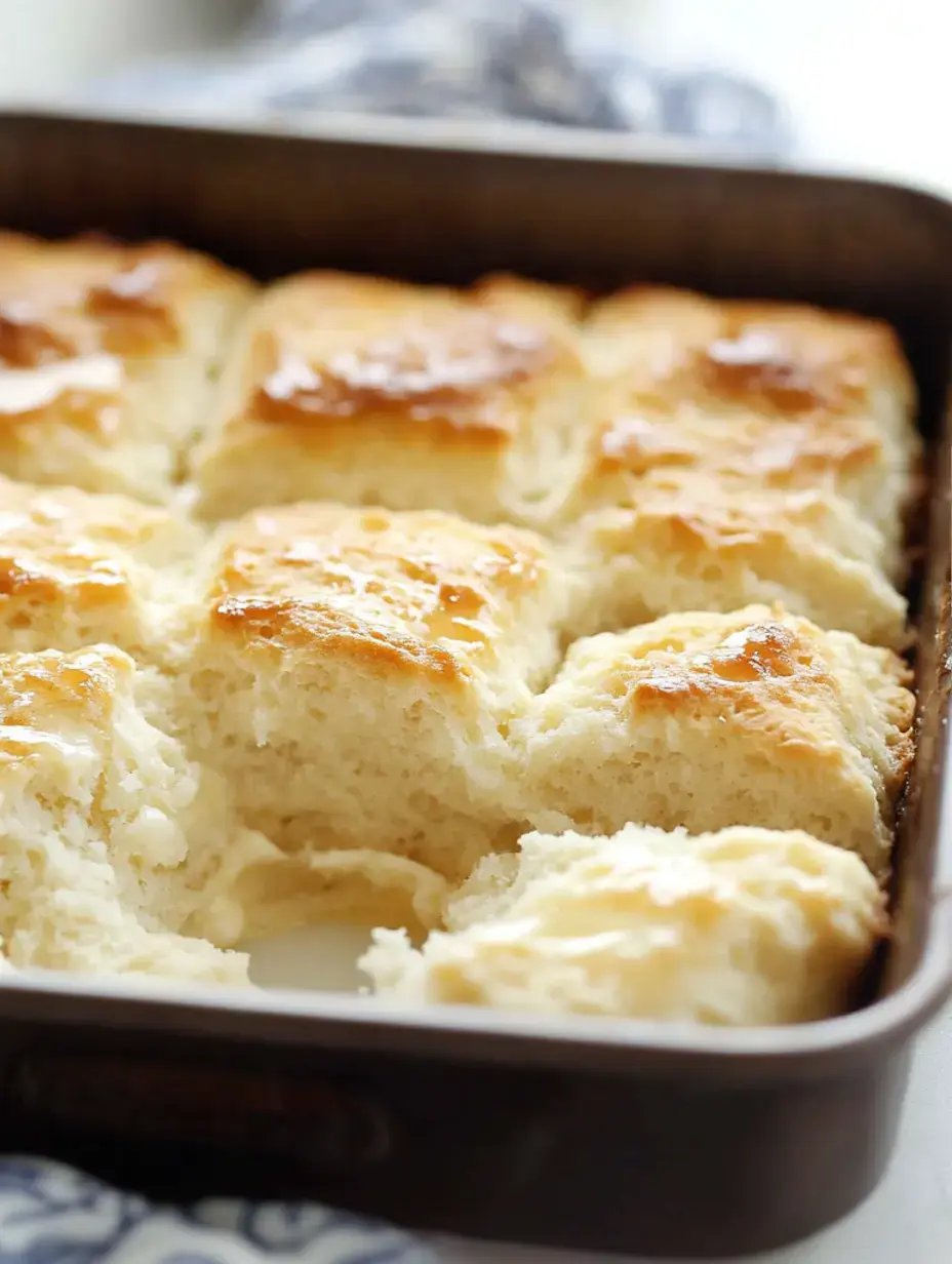 Frisch gebackene, goldbraune Brötchen auf dem Blech, einige auseinandergezogen und wunderbar fluffig innen.