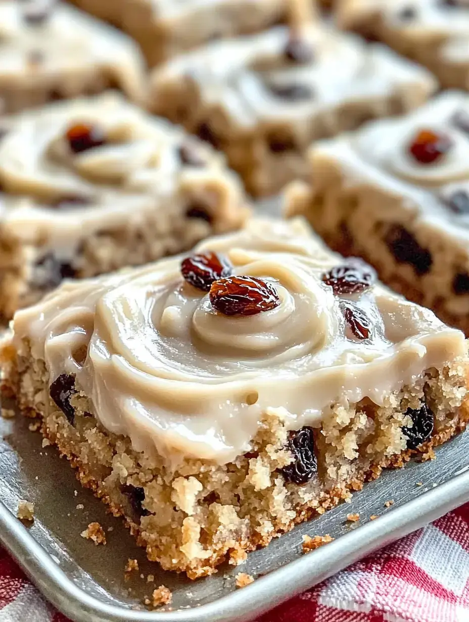 Ein saftiges Kuchenstück mit cremigem Frosting und Rosinen oben drauf, auf einer Silberplatte serviert.