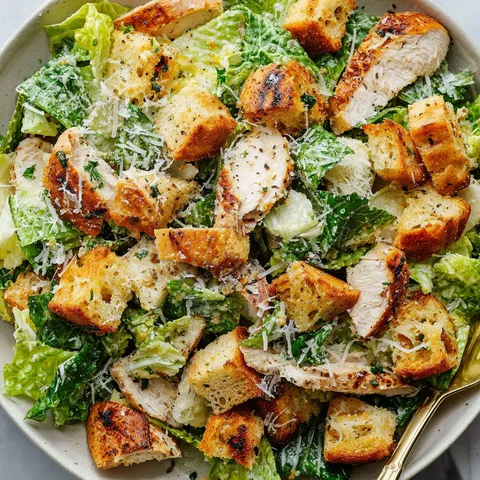 Ein Teller mit Huhn Caesar Salat und hausgemachten Broeseln.