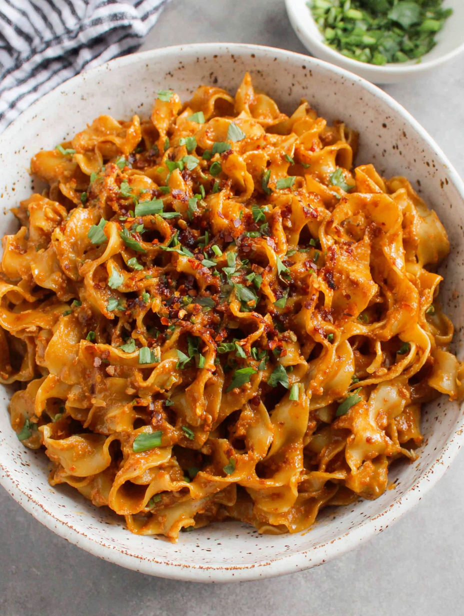 Eine Schüssel Pasta mit einem grünen Kraut oben drauf.