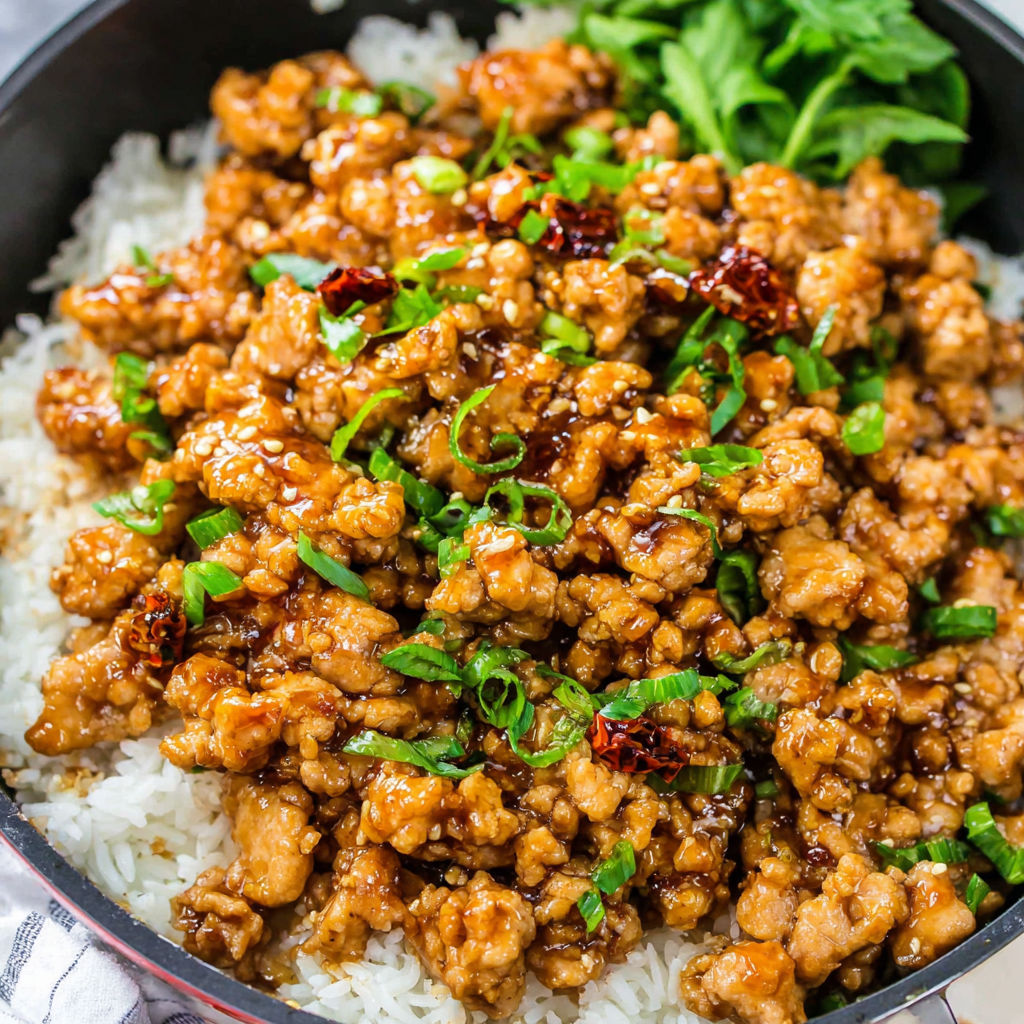 Eine Schüssel mit gemahlenem Orangenhuhn und Reis.
