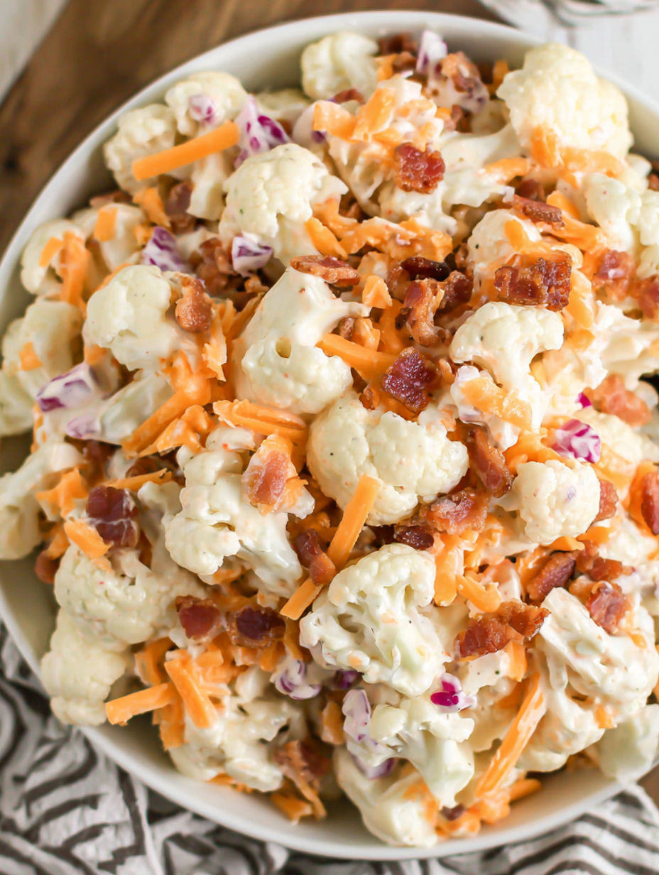 Eine Schüssel Blumenkohlsalat mit Käse und Speck.