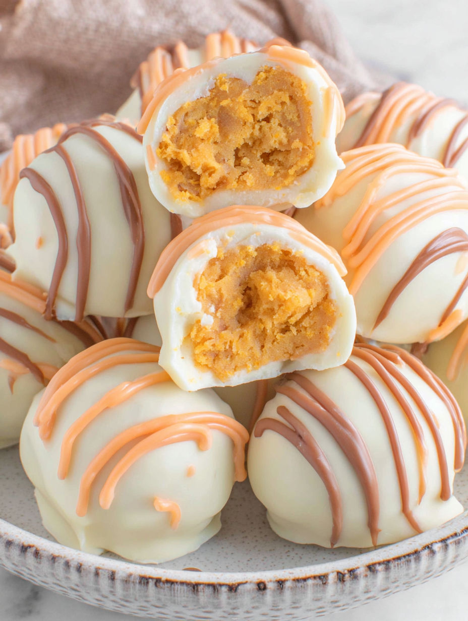 White chocolate pumpkin truffles on a plate.