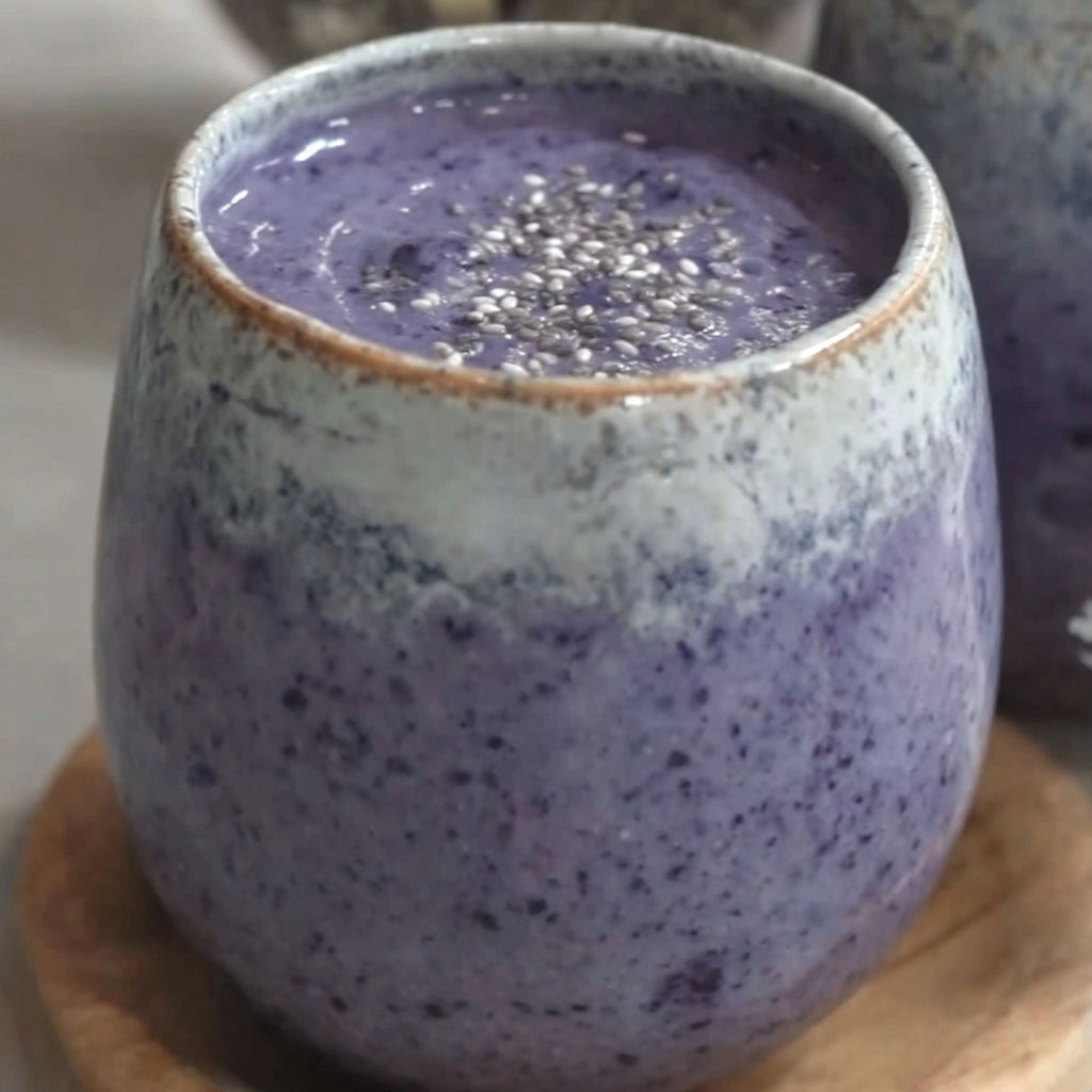 A glass of blueberry bliss tropical smoothie.