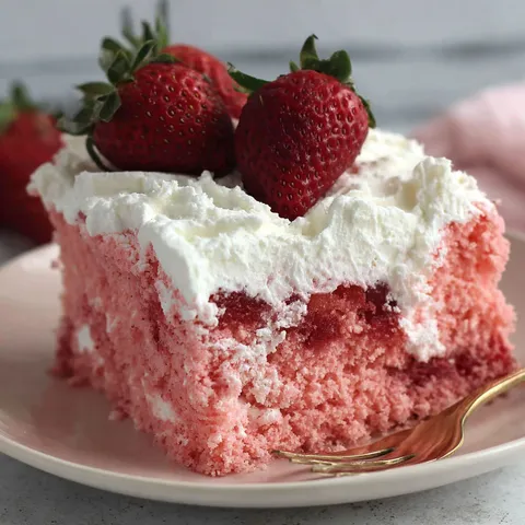 A slice of pink cake with white frosting and strawberries on top.