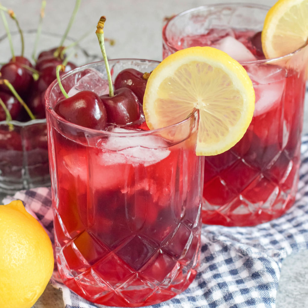 Zwei Gläser Kirschlimonade mit Zitronenscheiben darin.