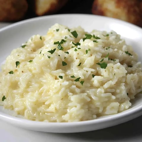 Nahaufnahme von cremigem Risotto mit gehackter Petersilie, serviert in einer weißen Schale.