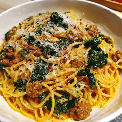 Eine Schüssel Spaghetti mit Fleisch und Spinat.