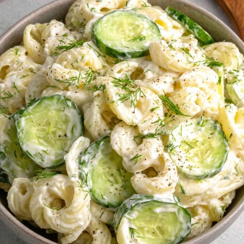 Eine Schüssel Nudelsalat mit Gurken und Käse.