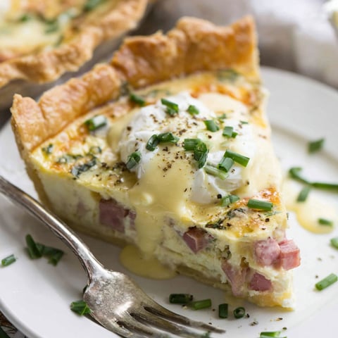 Eine Scheibe Quiche mit Eiern Benedict und Hollandaisesoße.