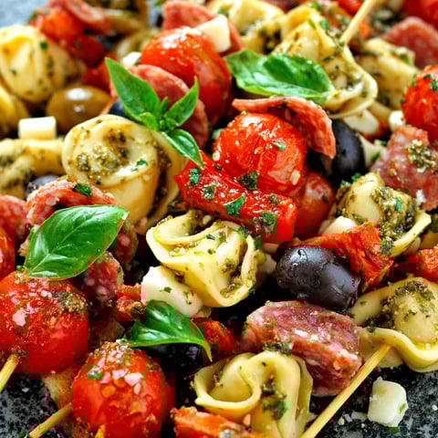 Ein Teller mit Tomaten, Oliven und Pasta.