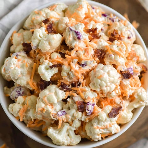 Eine Schüssel Blumenkohlsalat mit Speckstückchen.