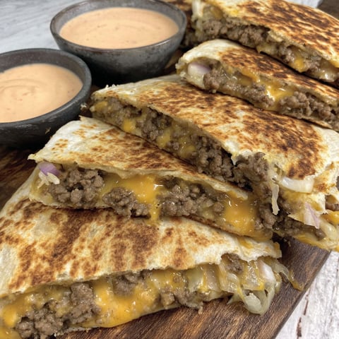 A stack of cheeseburger quesadillas with dipping sauce.