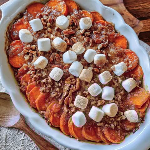 A dish of scalloped sweet potatoes with marshmallows on top.