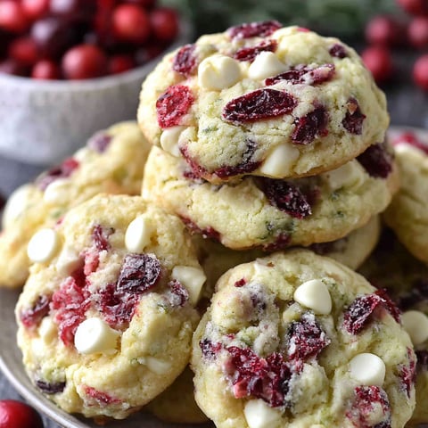 A plate of white chocolate cookies with red cranberries on top.