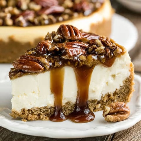 A slice of pecan pie cheesecake with caramel drizzle.