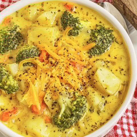 A bowl of soup with broccoli and potatoes.