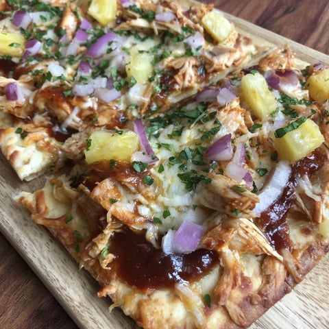A flatbread pizza with chicken, pineapple, and onions.
