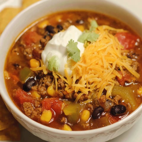 A bowl of soup with a dollop of sour cream on top.