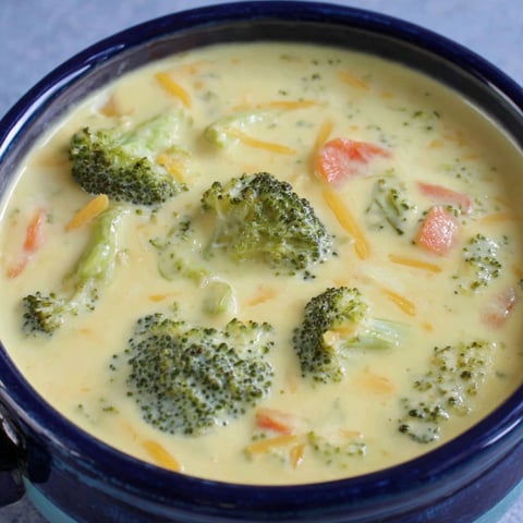 A bowl of soup with broccoli and cheese.