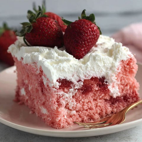 A slice of pink cake with white frosting and strawberries on top.