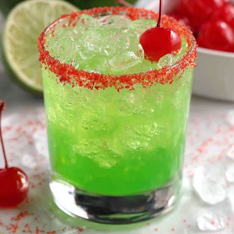 A green Grinch cocktail with cherries and lime.