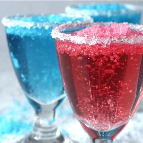 Two glasses of red and blue cotton candy champagne cocktails.