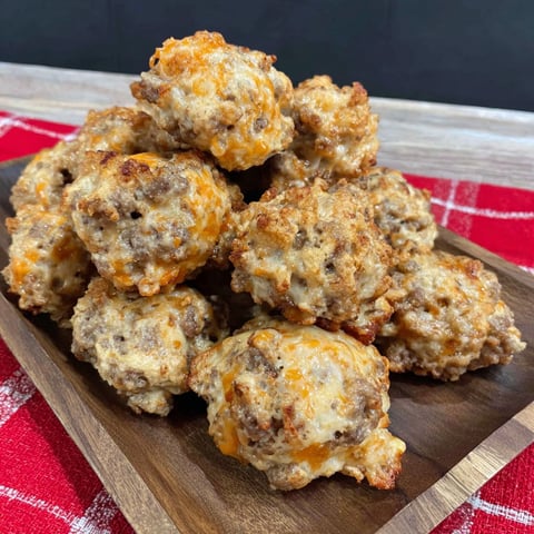 A stack of sausage balls on a wooden tray.